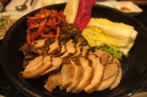 Bossam Meal – Sliced braised pork belly ready to be wrapped with various pickled vegetables 