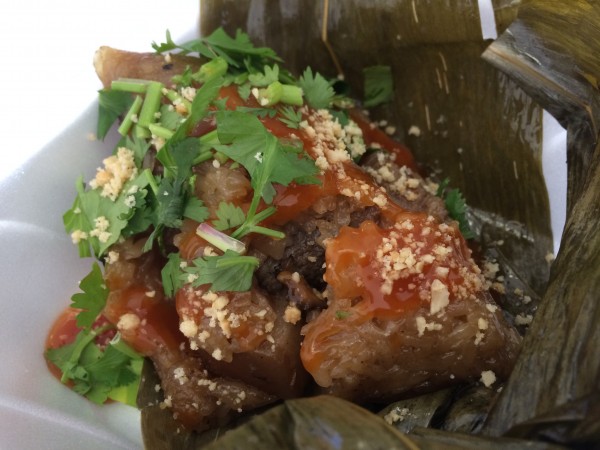 "Zong zi" - rice dumpling stuffed with pork belly, beef, and topped with a sweet and sour sauce, wrapped in banana leaf