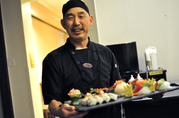 Chef Yoshi presenting a special sushi plate full of nigiri, sashimi, and a maki roll