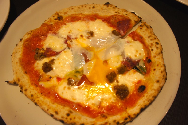 Margherita pizza with sausage, salami, and topped with egg